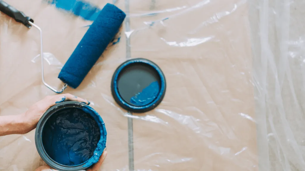 Pot of paint and roller brush on plastic